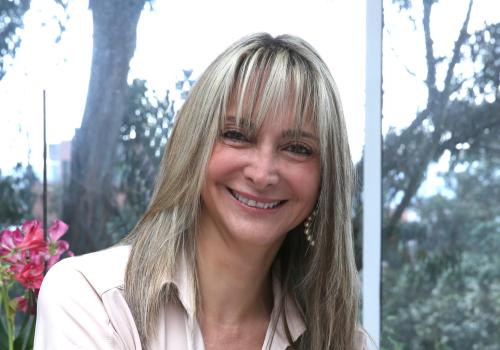 Mujer con cabello rubio sonriendo a la cámara