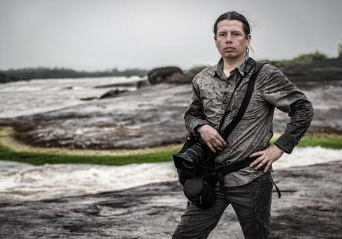 Fotografía de una persona posando con un paisaje oscuro