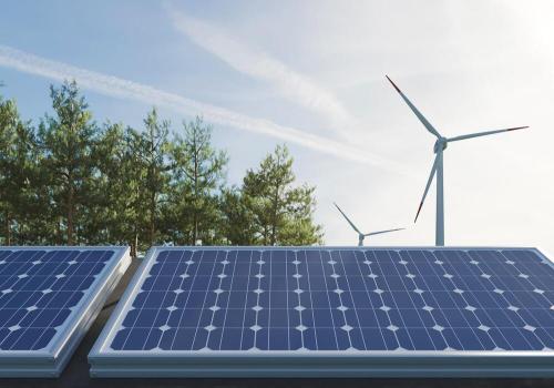 Foto de un panel solar y de fondo una de energía aeólica