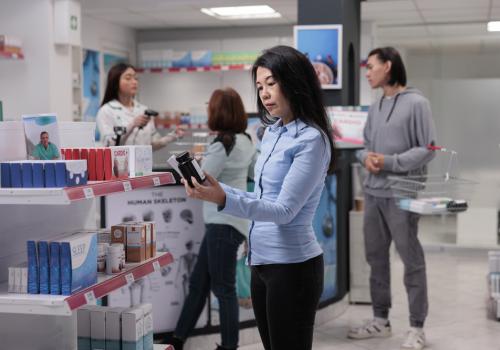 Foto d euna mujer en una tienda mirando un objeto en la mano