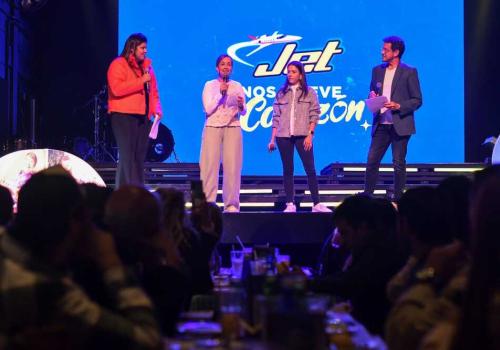 Foto de cuatro personas en un escenario con la marca jet de fondo