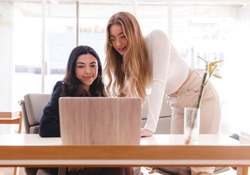 Foto de dos mujeres hablando con una computadora al frente