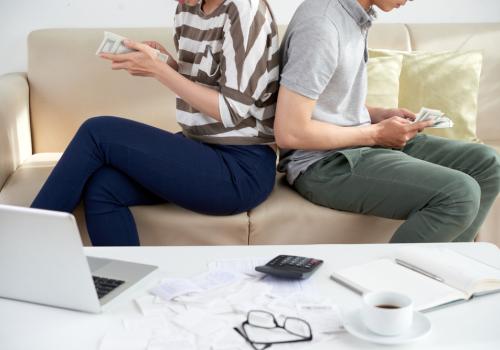 Foto de dos personas de espaldas contanto dinero sobre un sofa