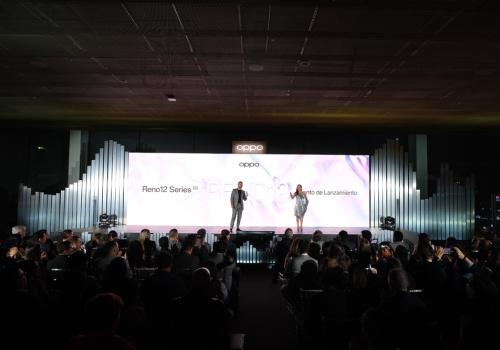 Foto de dos personas presentando frente a una gran pantalla de luz