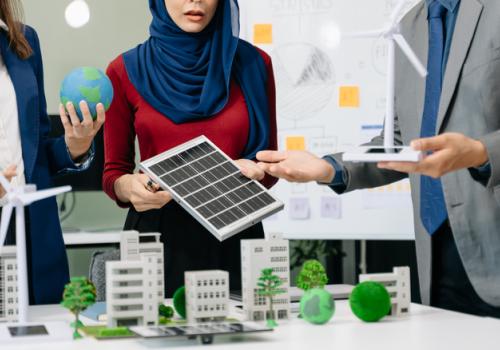 Foto de ejecutivos mirando un panel solar con un proyecto en la mesa