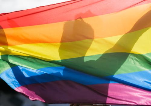 Foto de la silueta de un hombre detrás de una bandera inclusiva