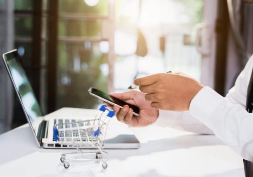 Foto de las manos de una persona comprando en línea por medio de un celular