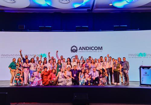 Foto de más de 10 personas reunidas frente a la cámara y un fondo de Andicom en el fondo