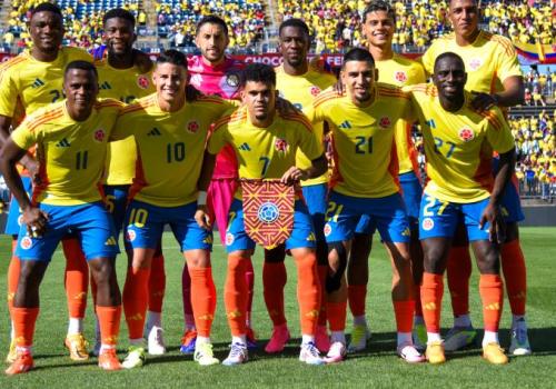 Foto de un equipo de fútbol tomados de los brazos con un fondo muticolor