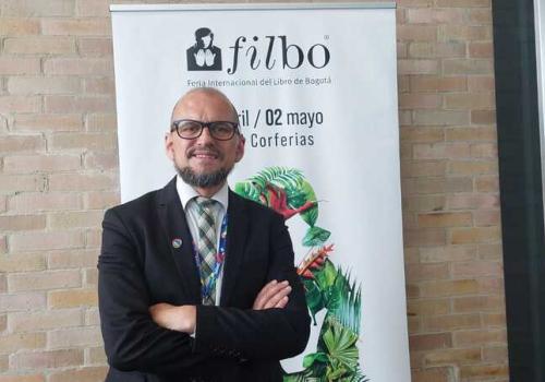 Foto de un hombre cruzado de brasil con barba y gafas negras mirando a la cámara