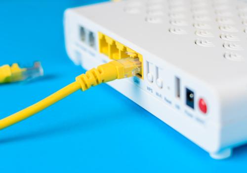 Foto de un modem blanco con cableado amarillo y fondo azul