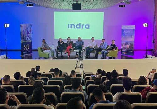 Foto de un panel con varias personas sentadas conversando frente a un auditorio