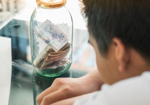 Foto de un señor mirando un frasco con dinero colombiano