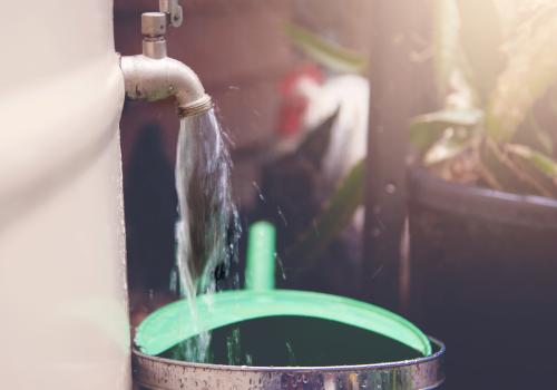 Foto de una llave de agua distribuyendo agua a un balde