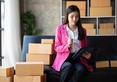 Foto de una mujer con blazer rosado con cajas al fondo