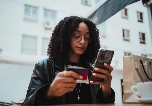 Foto de una mujer con un celular en la mano y una billetera en la otra