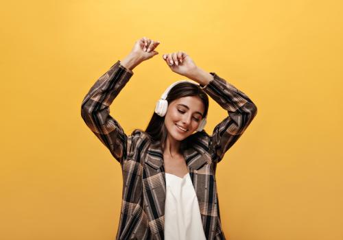 Foto de una mujer escuchando música con un fondo amarillo