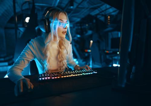 Foto de una mujer mirando un computador con unas gafas azules