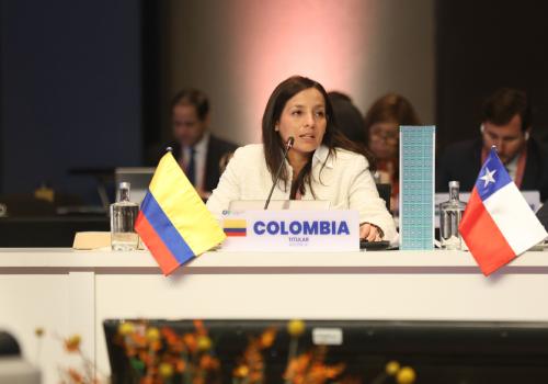 Foto de una mujer sentada en una mesa con banderas de colombia y chile