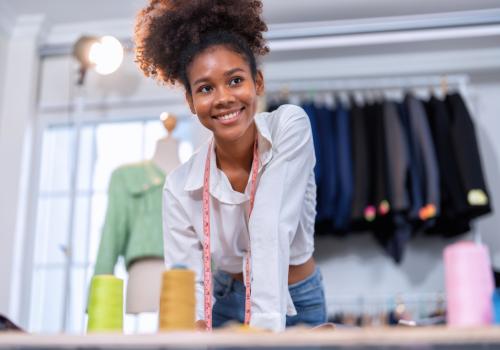 Foto de una mujer sonriendo a la cámara y de fondo unos vestidos