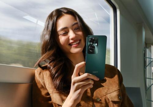 Foto de una mujer sonriendo con un celular verde en la mano