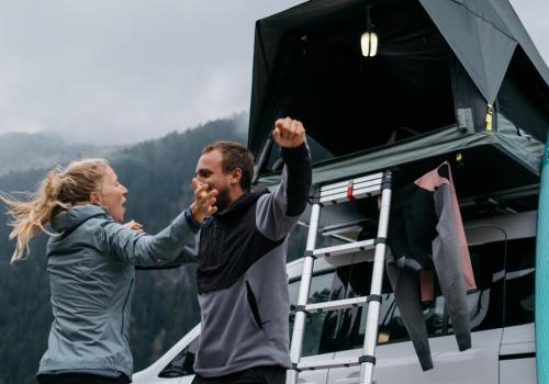 Foto de una pareja acampando con una carpa plegable de fondo