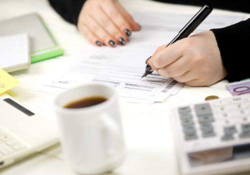 Foto de una persona escribiendo sobre un papel con hojas a su alrededor