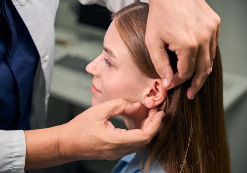 Foto de una persona revisando la oreja de una mujer