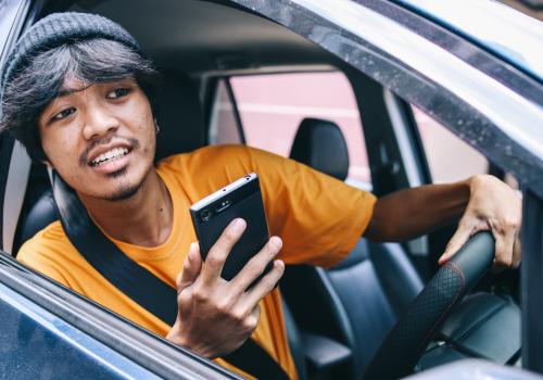 Foto de una persona sacando la cabeza por la ventana con un celular en la mano