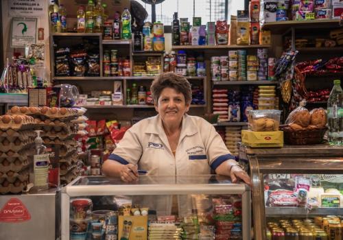 Foto de una señora frente a unos stands de una tienda de barrio