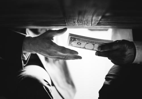 Foto de dos personas pasando dinero por debajo de la mesa