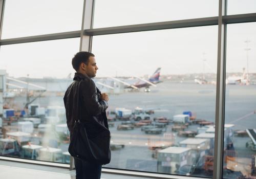 Hombre con traje negro mirando por la ventan de un aeropuerto