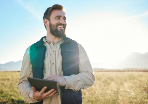 Hombre mirando el horizonte hacía la cámara con un paisaje rural