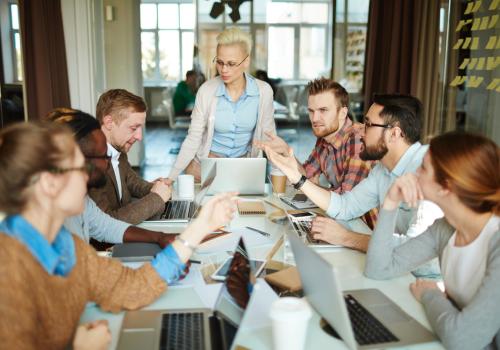 Hombres y mujeres en una mesa compartiendo ideas