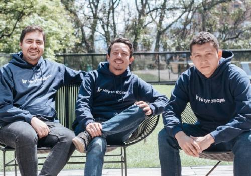 Tres jóvenes sentados, sonriendo a la cámara