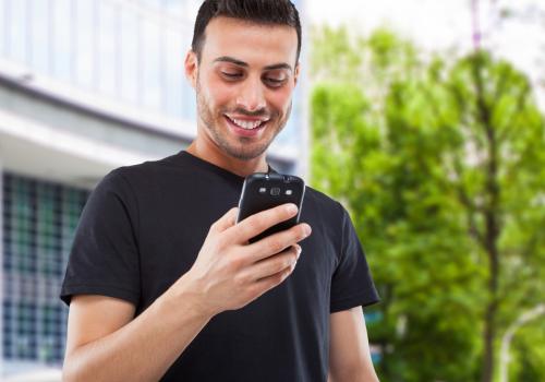 Foto de un hombre mirando al celular mientras sonrie