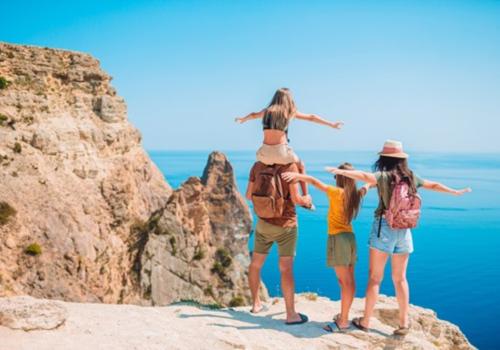 Imagen de una familia mirando al mar con un sol a sus espaldas