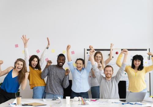 Foto de personas alzando las manos y sonriendo en sus oficinas