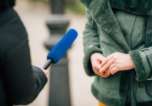 Foto de una persona con un micrófono azul entrevistando