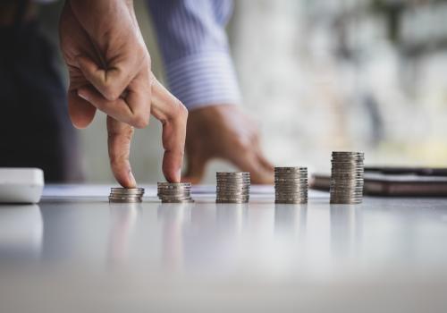 Monedas en una mesa y unos dedos pasando por ellas de forma escalonada