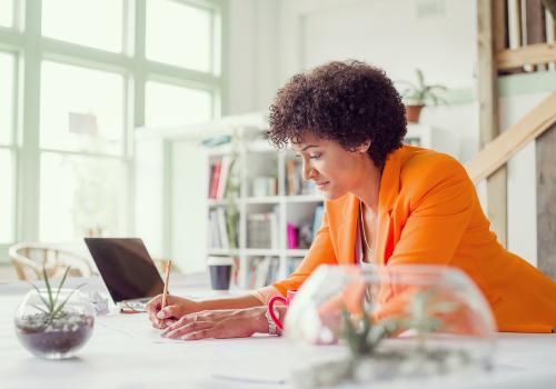 Mujer con blazer naranja mirando el computador