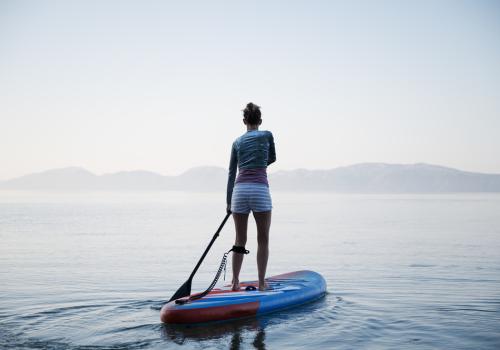 Mujer encima de una tabla en un lago