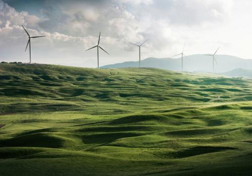 Paisaje de unas montañas y al fondo medios de propulsión de energía eólica