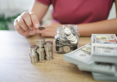 Persona recopilando monedas y billetes sobre una mesa