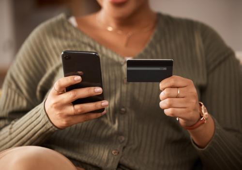 Persona sosteniendo una tarjeta en una mano y un celular en la otra