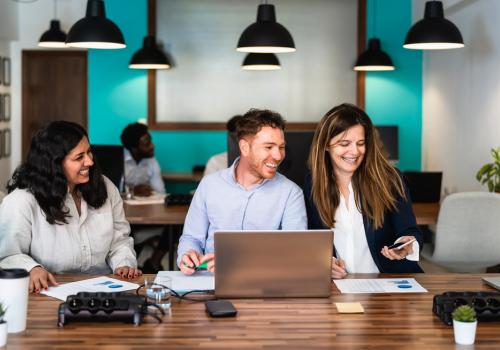 Personas en una oficina sonriendo frente a una mesa