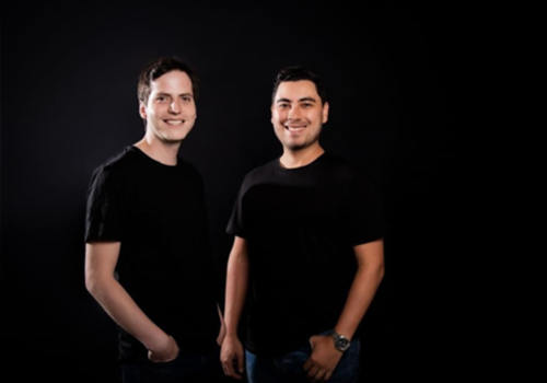 Foto de dos hombres con camiseta negra sonriendo a la cámara