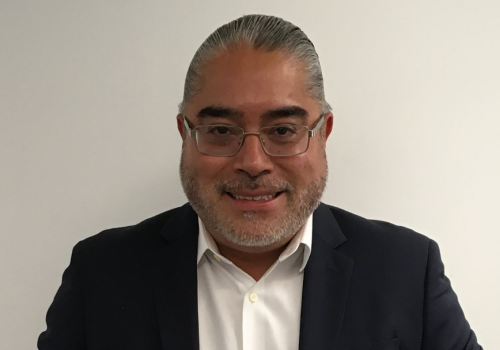 Foto de un señor con gafas blancas, mirando a la cámara con pelo hacía a trás