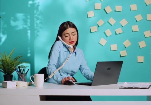 Mujer hablando por teléfono, mirando el computador y con muchos stickers pegados en la pared