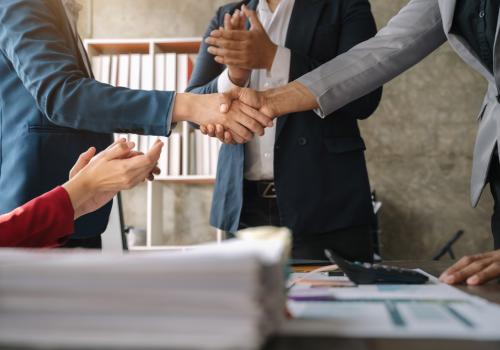 Foto de dos personas dándose la mano sobre una mesa